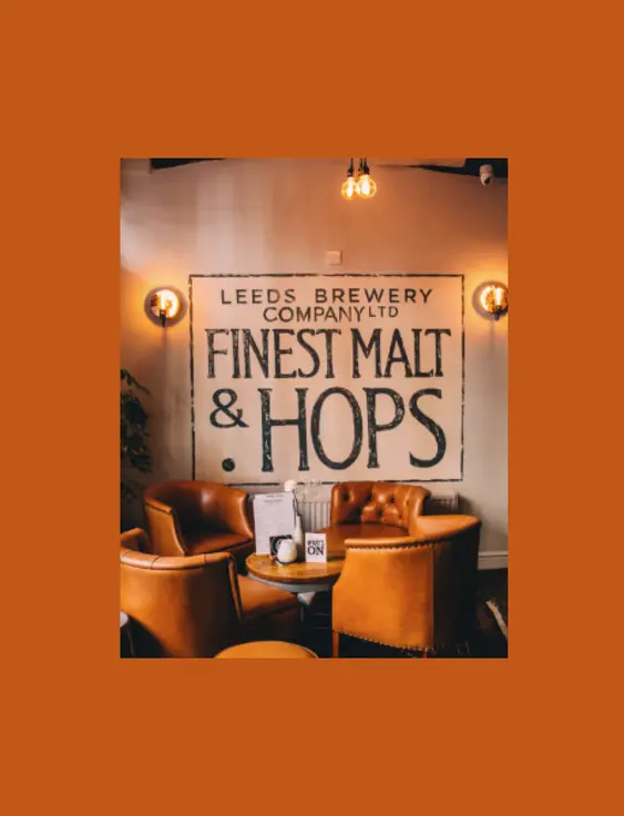 Warm pub interior with leather armchairs, under a sign reading 'Leeds Brewery Company Ltd Finest Malt &amp; Hops'.