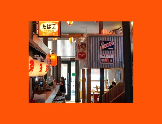 Japanese-themed restaurant interior with warm lighting, paper lanterns, and traditional  signs.